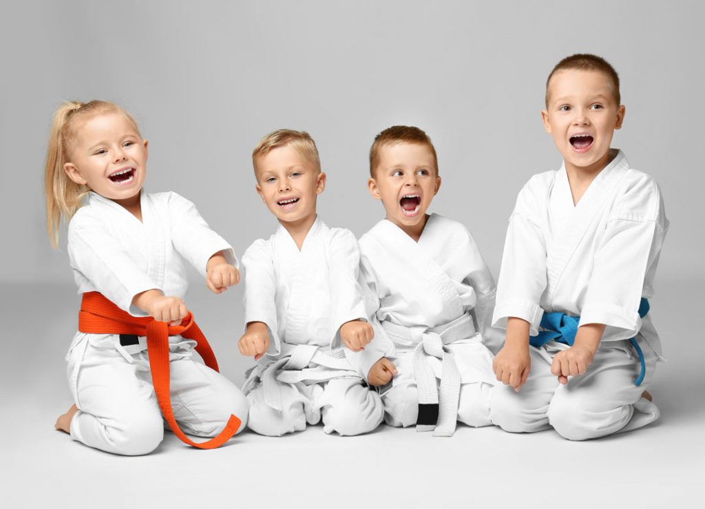 Young martial arts children showing ready stance while kneeling